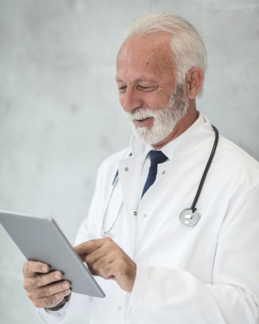 A physician in a white coat reviewing practice data on a tablet